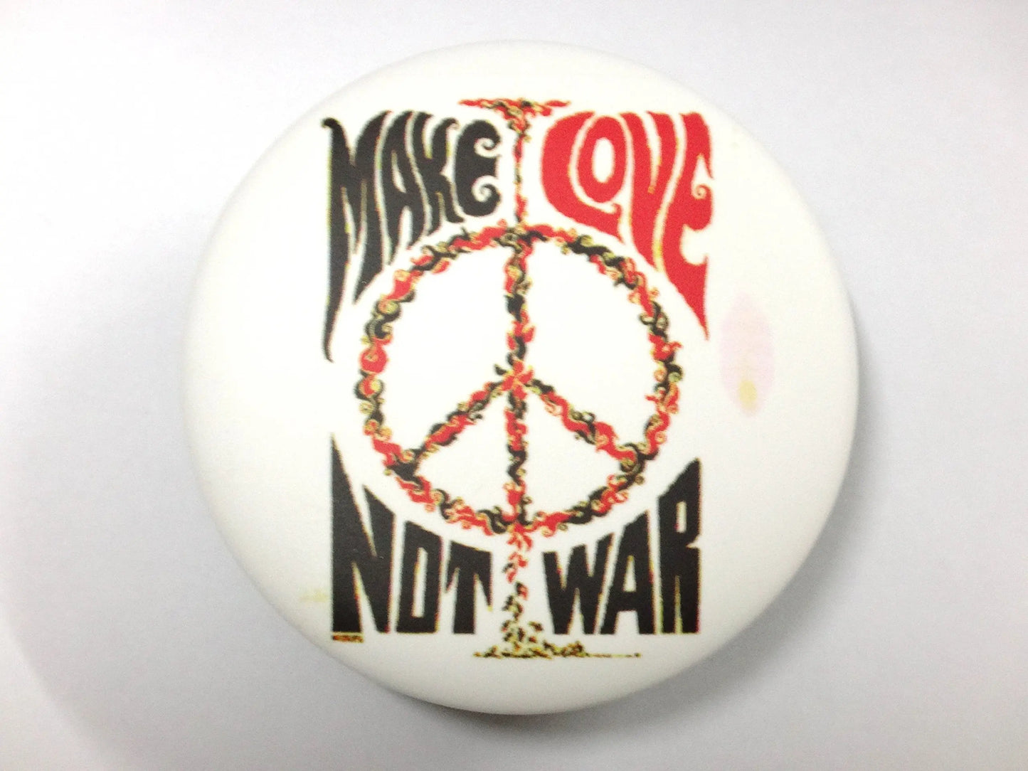 Peace-sign pinback button with red and black “NOT WAR” and peace/love text
