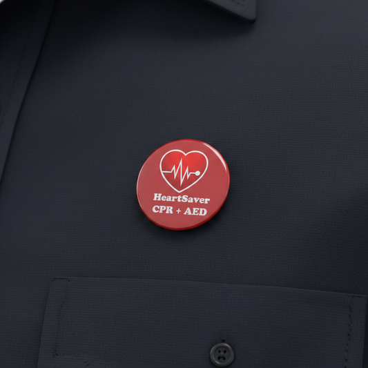 Red circular HeartSaver CPR+AED pinback brooch on dark fabric