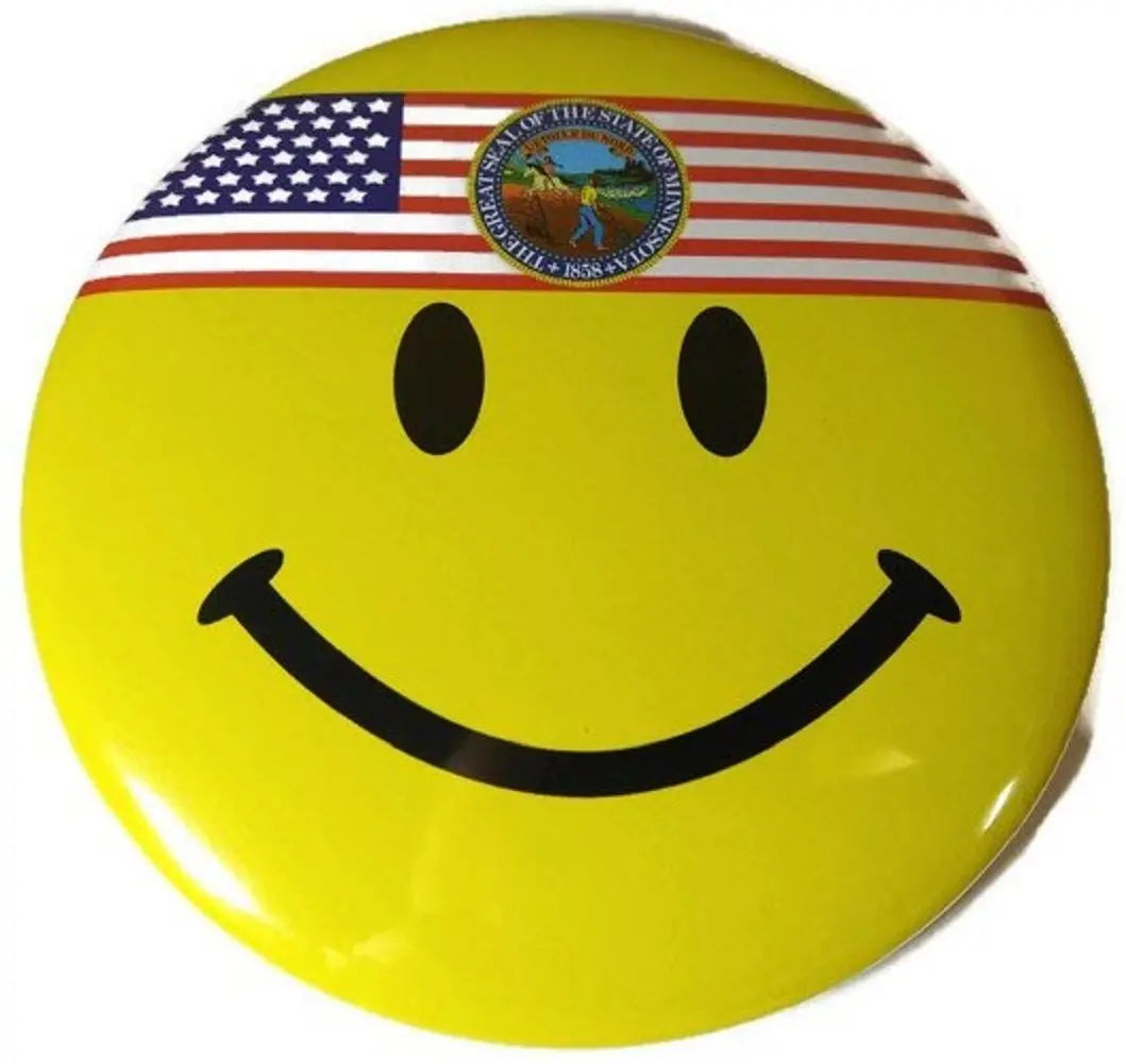 Round yellow smiley face button pin with black eyes and smile, topped with U.S. flag