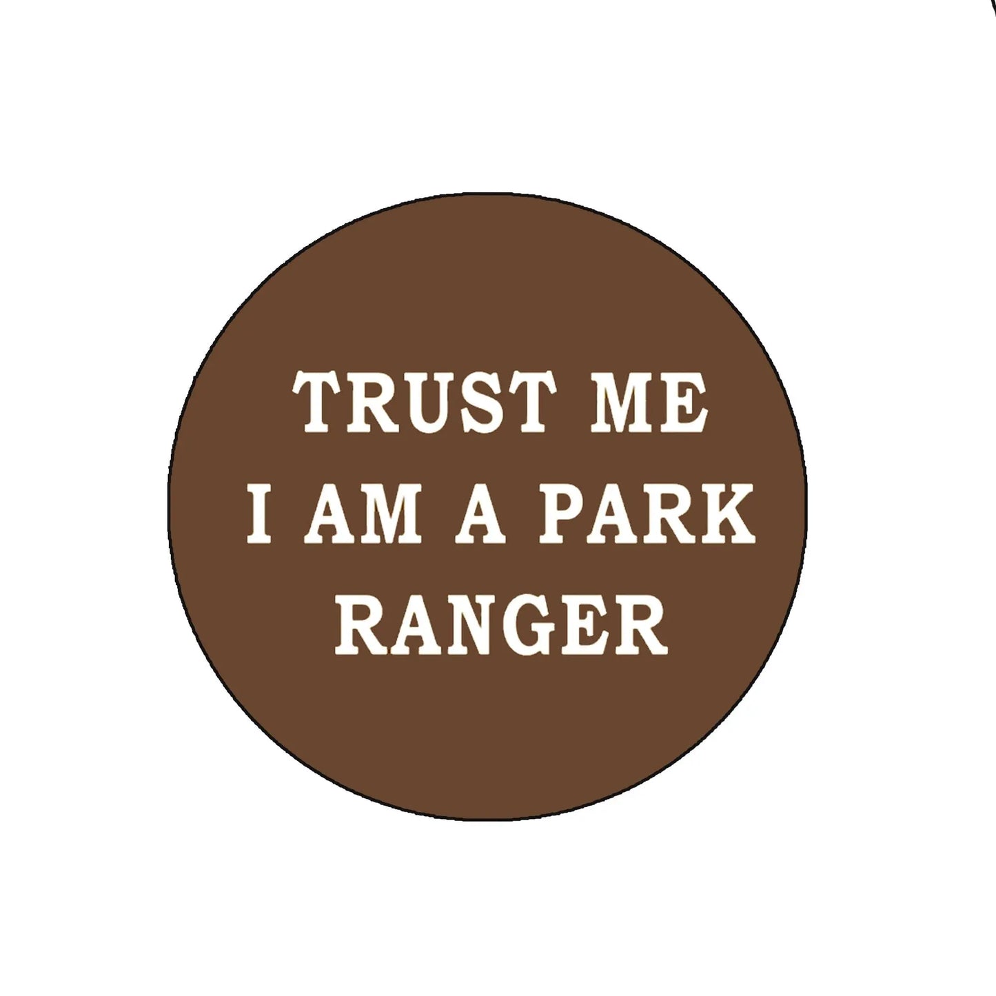 Brown circular park ranger pinback button with white text: “TRUST ME I AM A PARK RANGER”