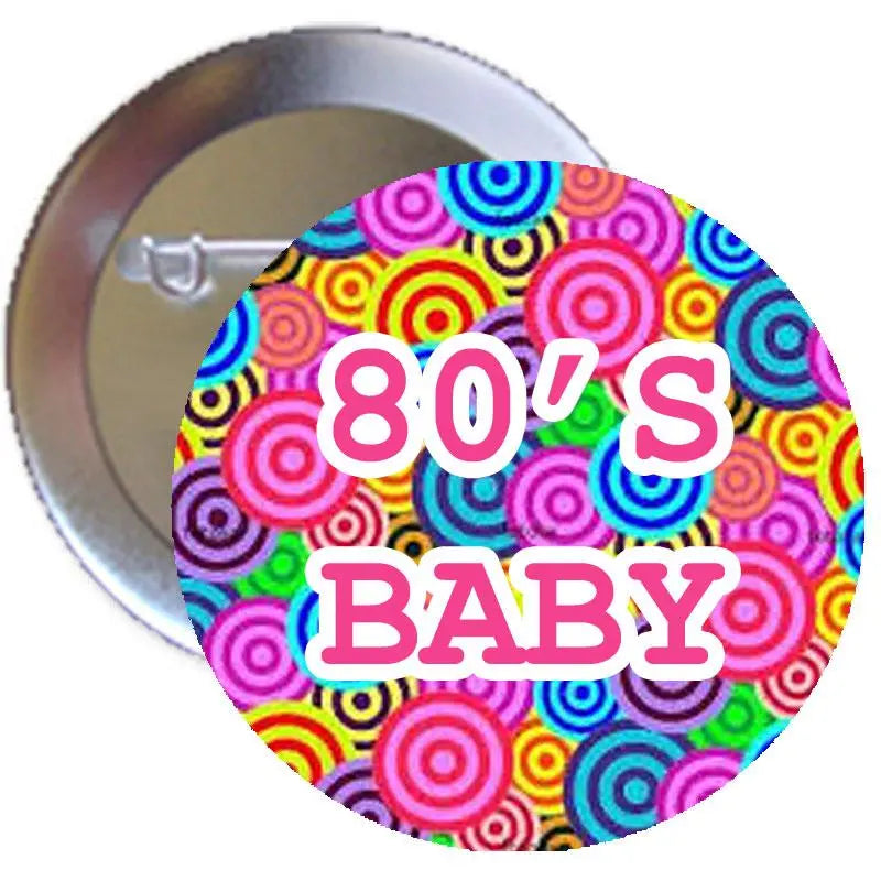 Round pinback button with multicolor concentric circles and pink text "80's BABY".
