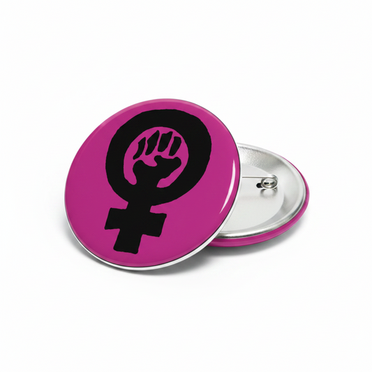 Feminist fist pinback button, pink circle with black raised hand symbol, silver back clasp