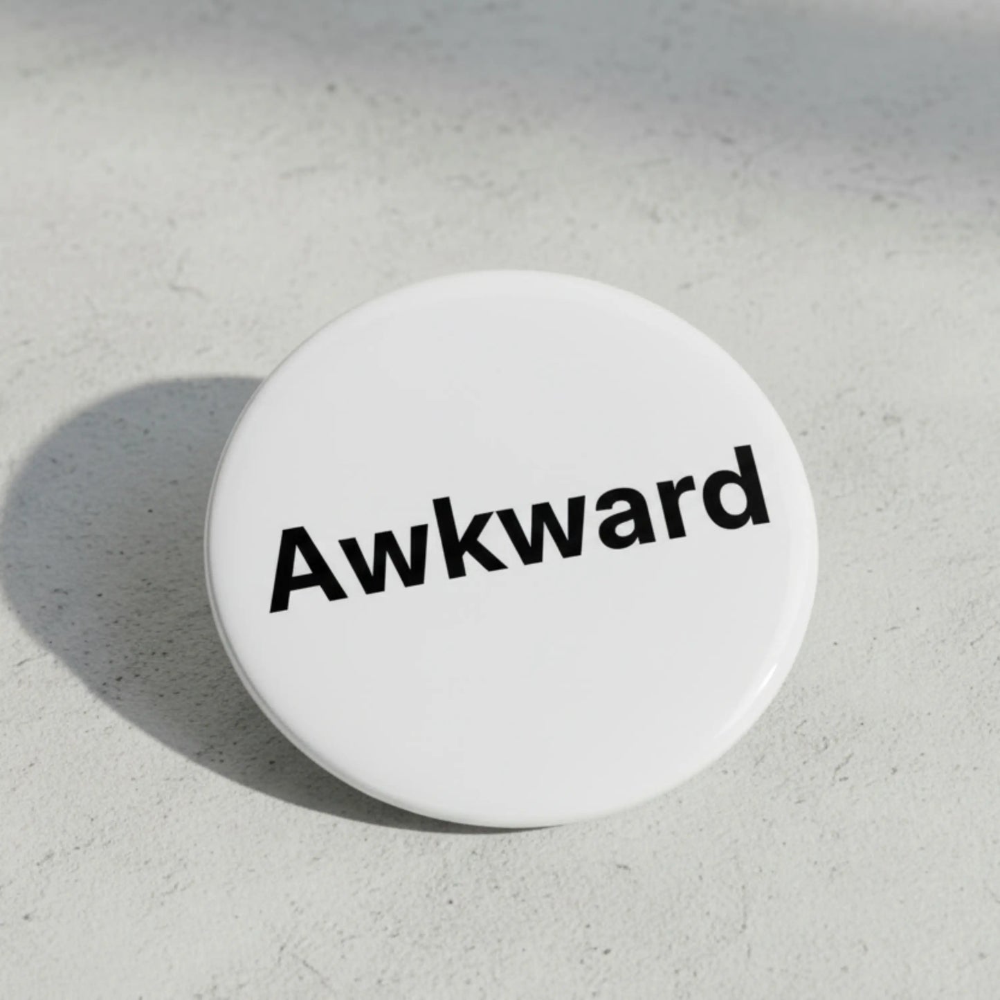 Awkward pinback button, white enamel with black “Awkward” text