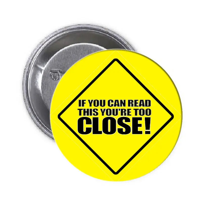 1.25-inch pinback button, yellow with black text 'If you can read this you're too close'