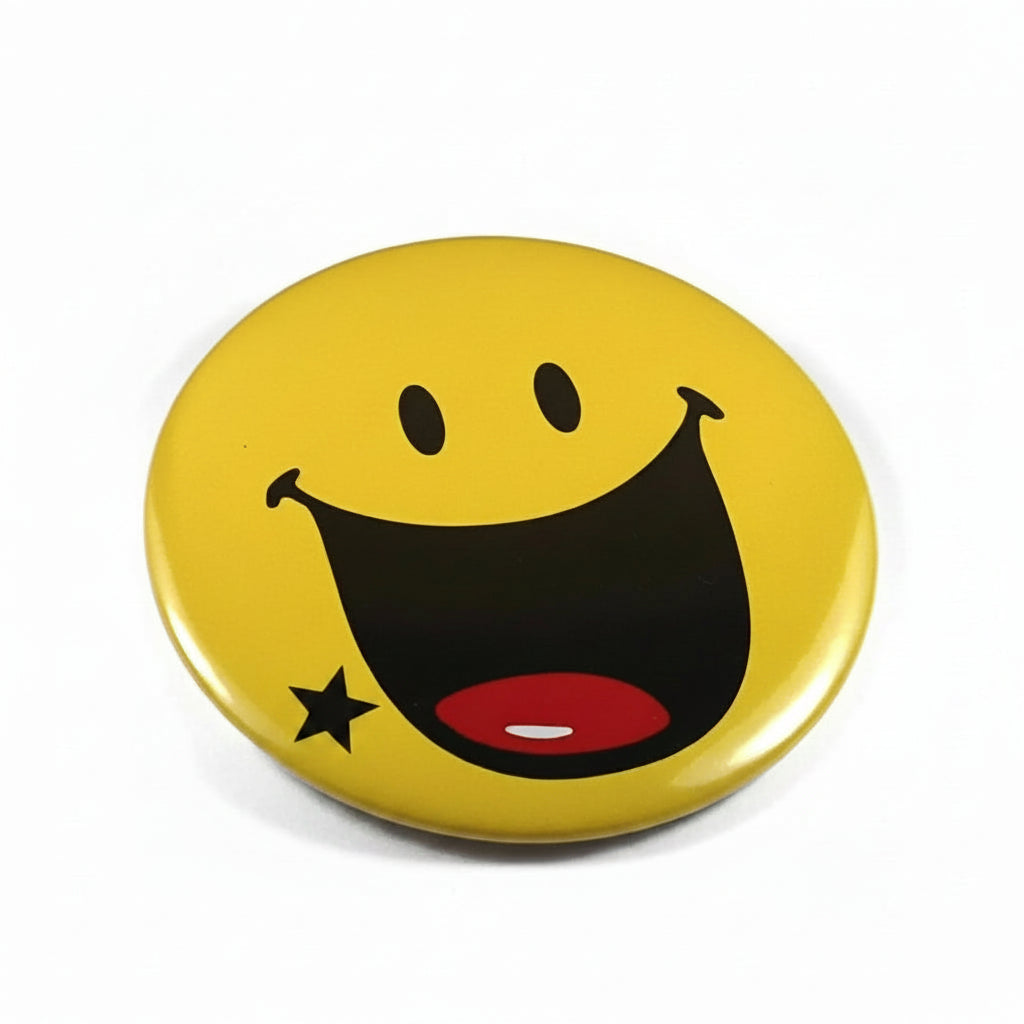 Yellow emoticon pinback button with black smile, red tongue, and star detail