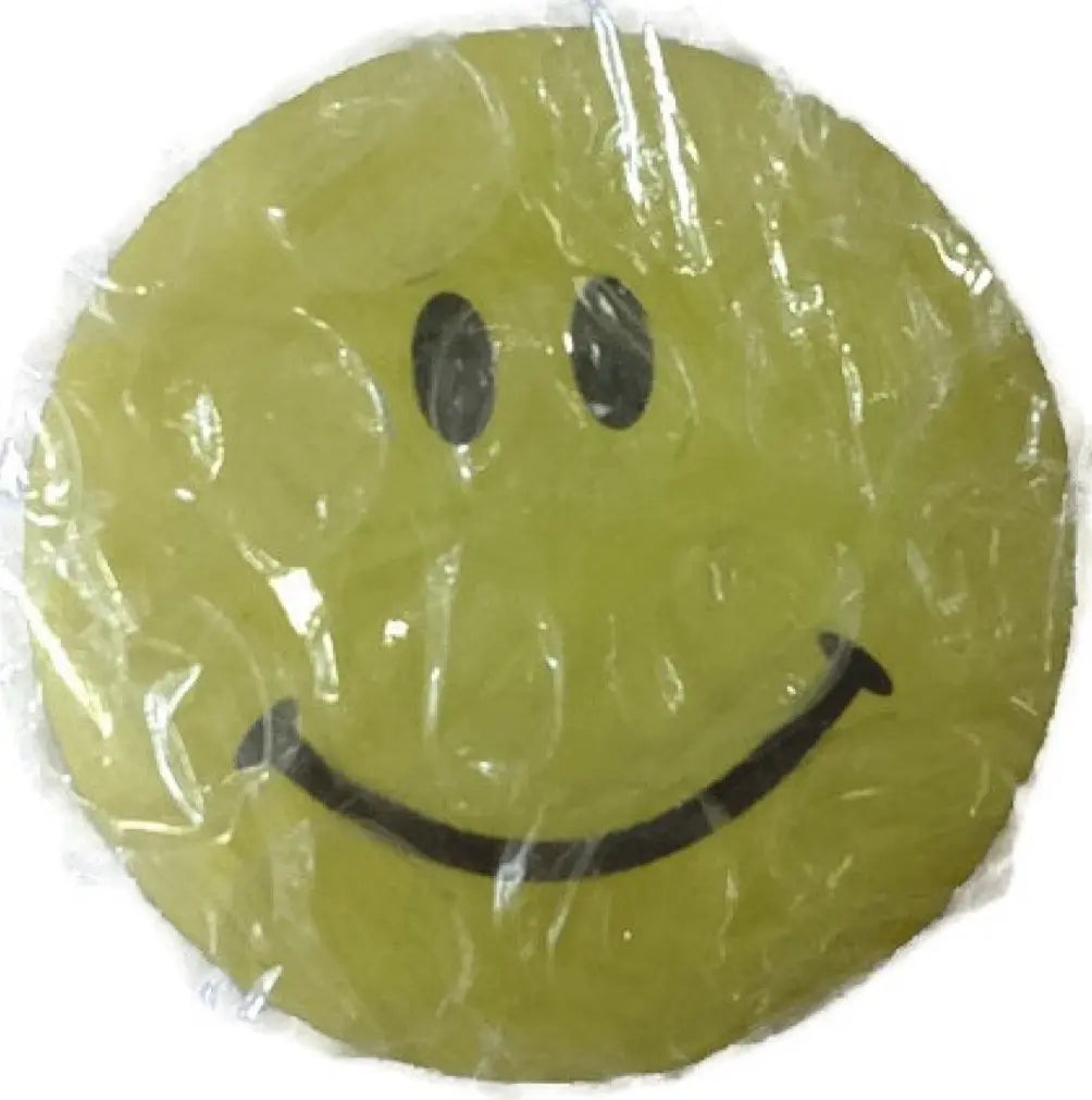 Green round smiley face pin badge with black eyes and curved smile