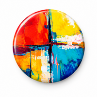 Two round pinback buttons shown on a white background, with one button displaying a colorful abstract painted design in red, yellow, blue, orange, and white, and the other showing the metallic silver back with pin hardware.
