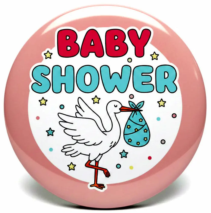 A round pink baby shower button badge featuring a white stork carrying a blue baby bootie and the words 'BABY SHOWER' in red and blue lettering.