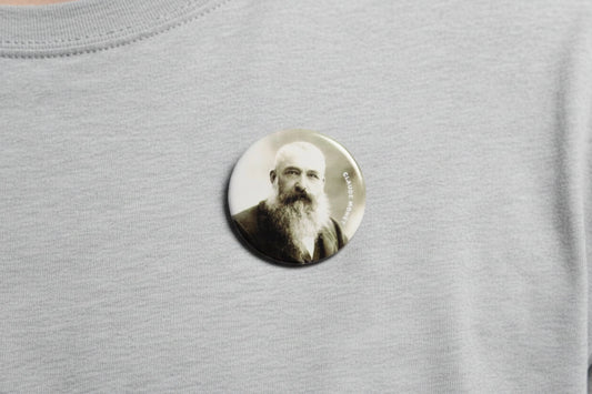2.25-inch round pinback button with Claude Monet portrait, worn on heather gray shirt