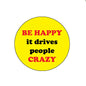 Yellow round pinback badge with red text: BE HAPPY, it drives people CRAZY