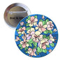 Floral pinback button brooch with pink and cream blossoms on blue background.