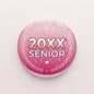 Pink round pinback badge, '20XX SENIOR' and floral laurel design