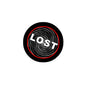 Round pinback button, black with red rim; 'Lost' text and hypnotic swirl lines.
