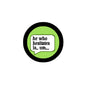 Round pinback button with black edge, lime green center, and “he who hesitates is... um” text