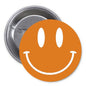Orange retro smiley face pinback button with white grin, metal back visible