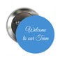 Round blue pinback button with white 'Welcome to our Team' text