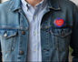 Red heart enamel pin badge on blue denim jacket