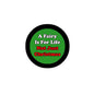Green round pinback button with black border, slogan text about fairy life and Christmas
