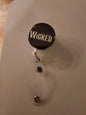 Just Wicked retractable badge reel with black round Wicked logo face and metal clip
