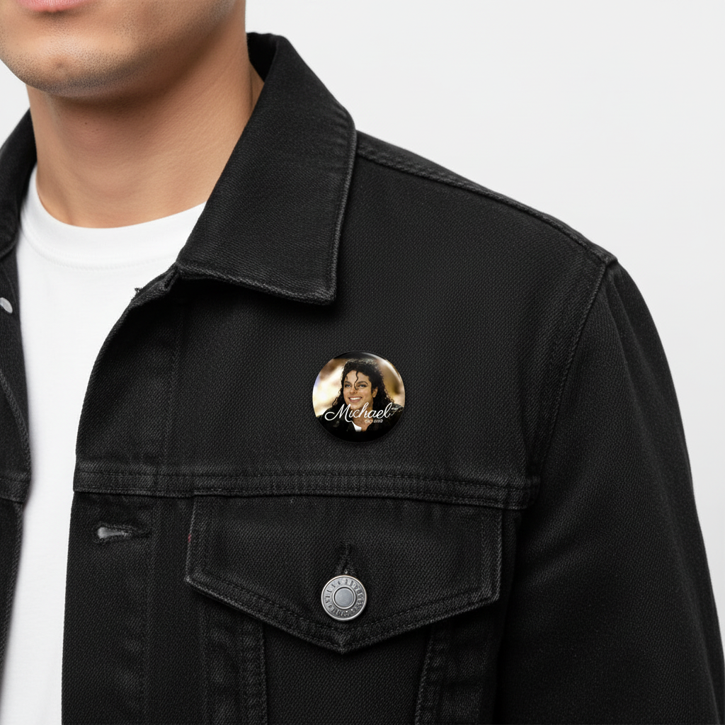 A close-up of a person wearing a black denim jacket over a white t-shirt, featuring a circular pin badge on the chest with a portrait and the name 'Michael'.