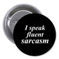Black 1.25-inch pinback button with white text "I speak fluent sarcasm"