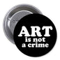 Black pinback button with white text “ART is not a crime” and metal backing