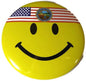 Round yellow smiley face button pin with black eyes and smile, topped with U.S. flag