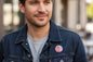 Round colorful pinback button on dark denim jacket, small lapel accessory