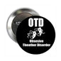 Round metal pinback button with black face, white OTD and Theather Disorder masks text
