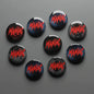 Set of 8 round pinback buttons, black with red “MANIAC” lettering, 1.25-inch