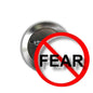 Round metal pinback button featuring “FEAR” text crossed out in red