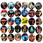 A collection of 30 vintage horror movie and cult film pinback buttons arranged in a grid on a dark surface. The buttons feature various iconic movie posters and artwork, including titles like 'The Fly', 'Child's Play', 'A Nightmare on Elm Street', 'The Exorcist', and 'The Ring'.