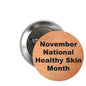 Orange round pinback button with 'November National Healthy Skin Month' text