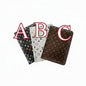 Three passport cover holders with monogram pattern, dark and light brown sleeves