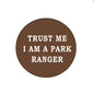 Brown round pinback button with white text: "TRUST ME I AM A PARK RANGER"