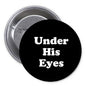 1.25-inch black pinback button with white text 'Under His Eyes'