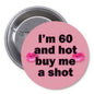 Pink round pinback button, black text: 'I'm 60 and hot, buy me a shot'