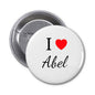 Round pinback button with safety pin, white face with "I" heart and "Abel" text
