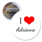 Circular pin-back button: white front, black 'I Adrienne' script, red heart