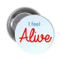 Round pinback button with light blue face, red “Alive” and blue “I feel” text