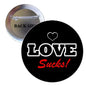 Black pinback brooch with white LOVE text, red “Sucks!” and small heart.