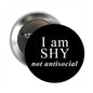 Round black enamel badge pin with white text 'I am SHY not antisocial'