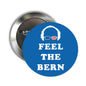 Blue pinback badge with “FEEL THE BERN” text and a person wearing headphones