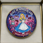 Round enamel pinback with Alice character art, blue dress and gold border, 2.25-inch