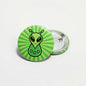 Alien green pinback button with striped alien face and metal safety pin back