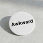 Awkward pinback button, white enamel with black “Awkward” text