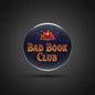 Round navy pinback button with open-book icon and orange “BAD BOOK CLUB” text