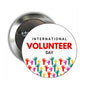 Round silver pinback button with “International Volunteer Day” and colorful raised hand icons