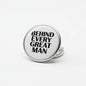 Round silver pinback button with black 'BEHIND EVERY GREAT MAN' lettering