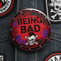 Being Bad pinback button, round metal badge with 'Being Bad' text and skull